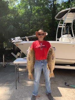 Dr. Hamilton holding two fish in front of a boat